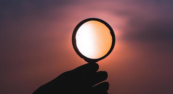 A hand holding a magnifying glass.